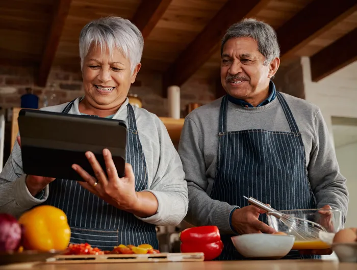 couple looking at an iPad and cooking in the kitchen