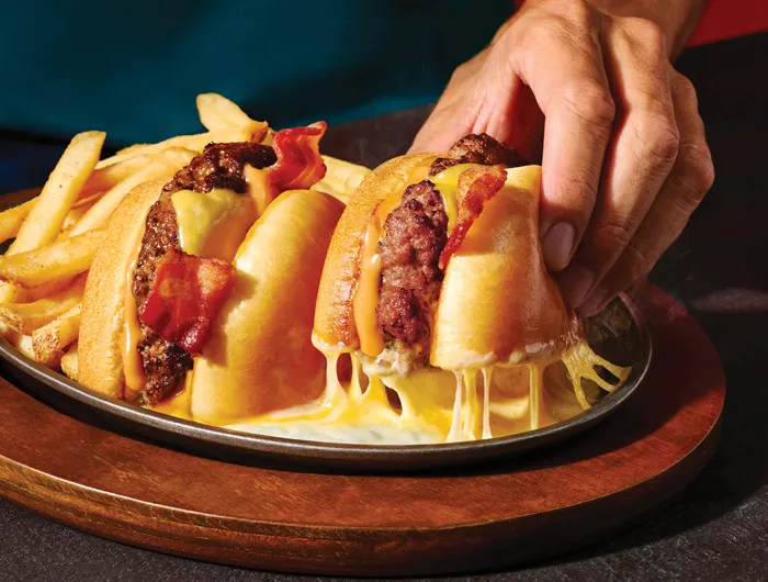 Applebee's O-M-Cheese Burger and fries with a hand picking up on half of the burger