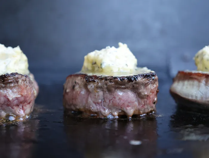 Eye fillet steaks on a grill topped with garlic butter