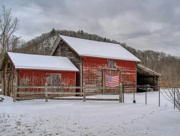 A shabby red barn with an American flag hanging on the side