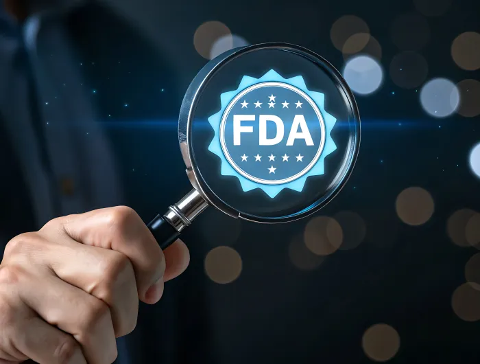 A man holding a magnifying glass with the FDA logo reflected in the glass