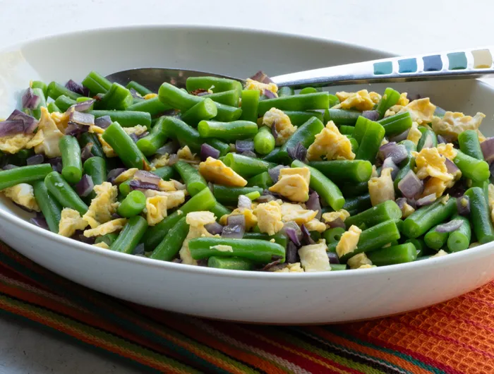 white bowl with green beans, egg and chopped onion