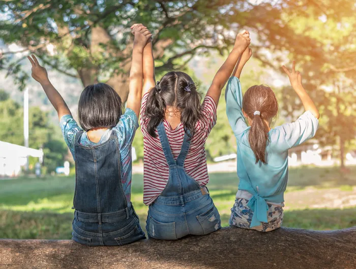 three kids sitting on a tree branch