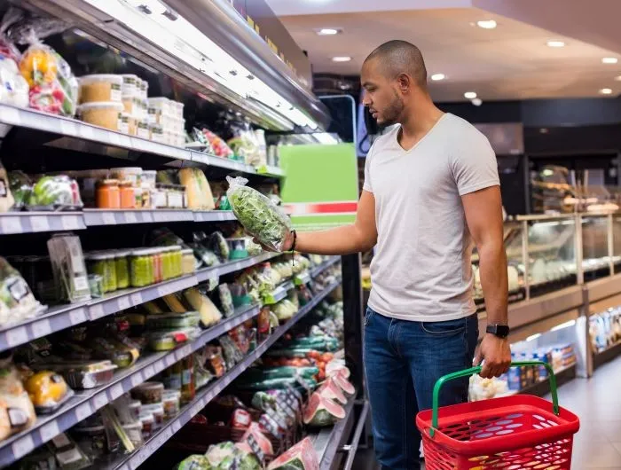 A man shops for bagged salad