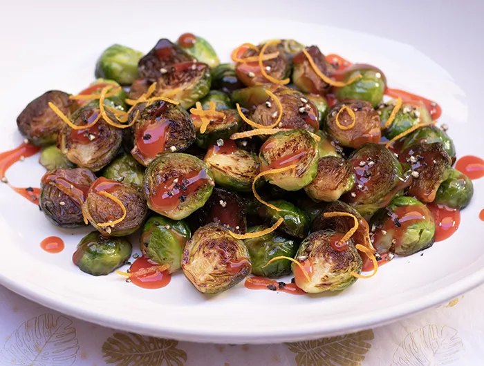 plate of Brussel sprouts halved, roasted and covered in a sauce