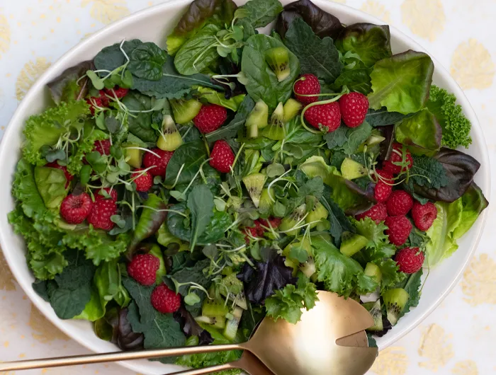large plate filled with salad greens and berries