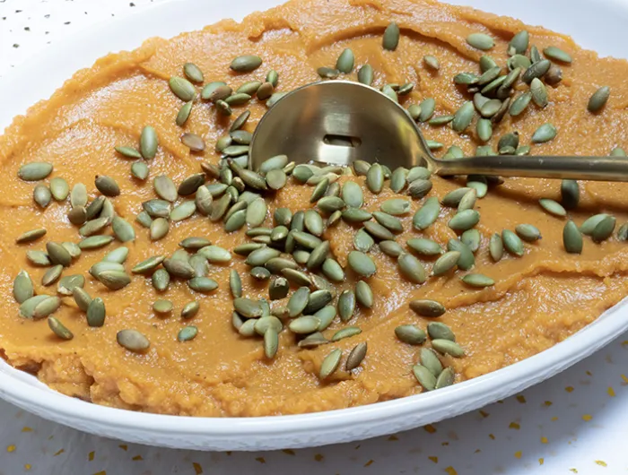 large bowl of sweet potato and butternut mash topped with pumpkin seeds