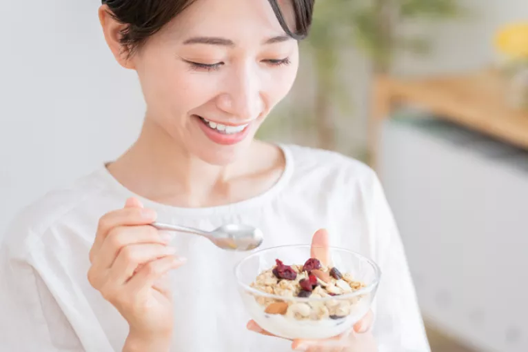 woman eating a small yogurt parfait out of a clear bowl