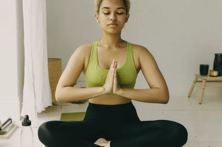 woman sitting crisscross with prayer hands as a yoga pose