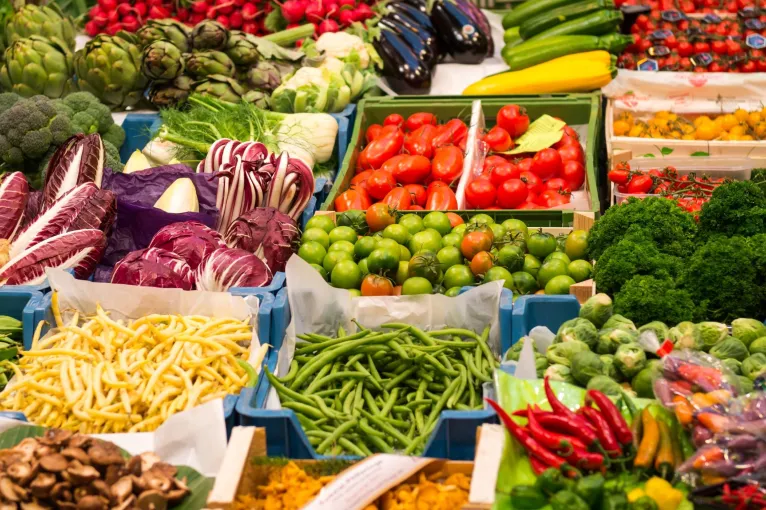 A produce market stall with a variety of colorful seasonal fruit and vegetables on offer