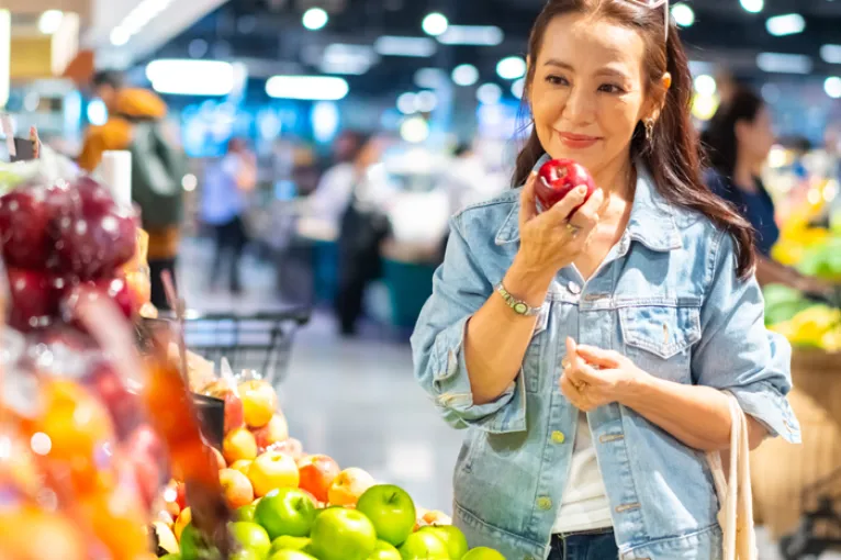 woman at grocery store holding a apple in the produce section