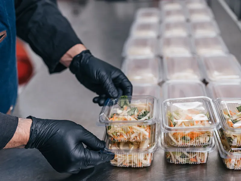 Food in disposable dishes ready for delivery. The chef prepares food in the restaurant and packs it in disposable lunch boxes.