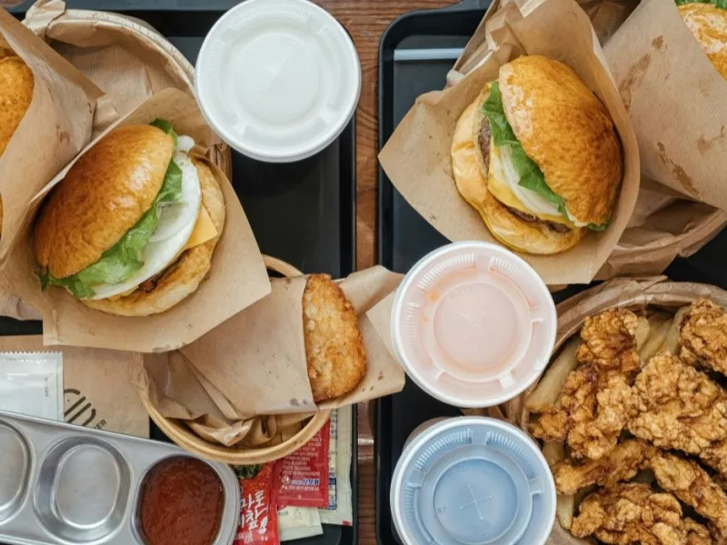 Flat lay of fast food burgers and fried foods with soda