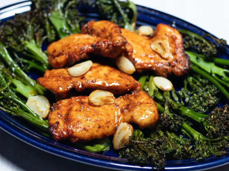 dark blue plate with broccolini and chicken