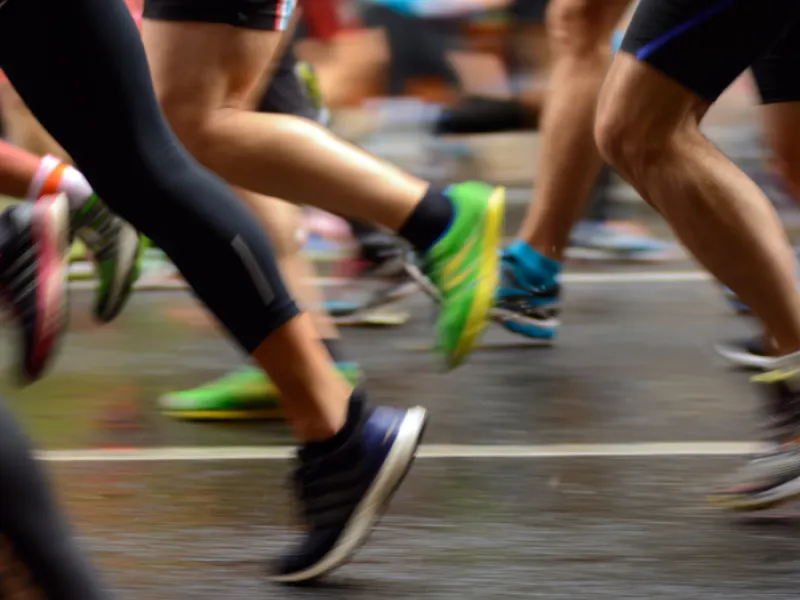legs and feet of runners passing on a road