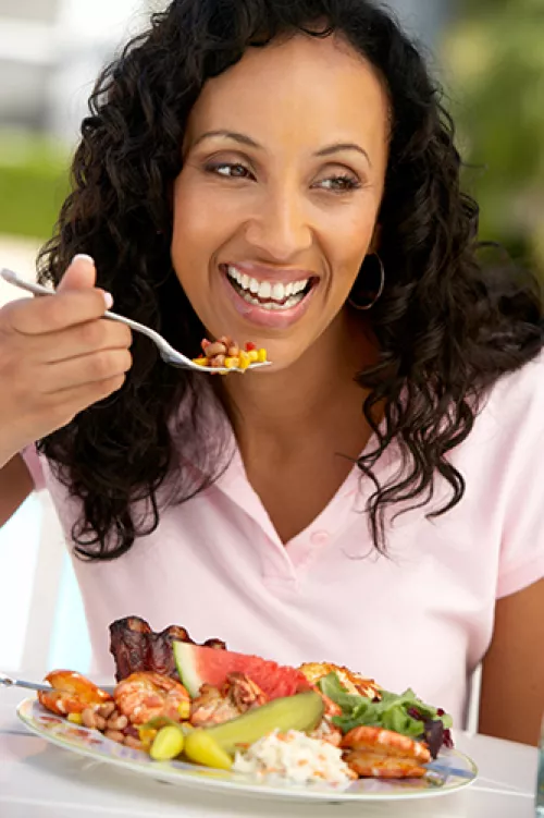 woman in pink short eating from a full plate of food