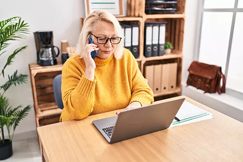 woman on phone while looking at computer