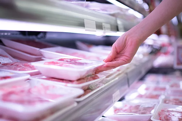 hand reaching for meat in the grocery store