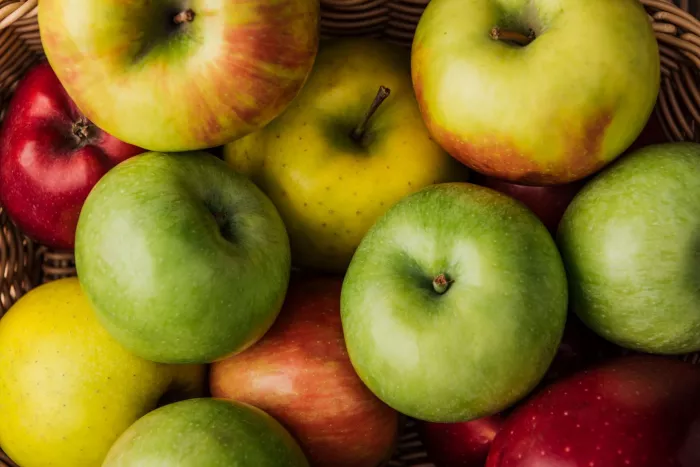 Seasonal produce - a closeup of many apple varieties in a wicker basket