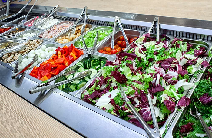 salad bar with tubs of various veggies and leafy greens