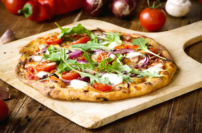 pizza topped with various veggies on a wood pizza slate