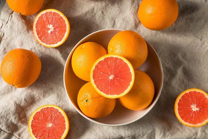 cara cara oranges in a bowl with some cut in half showing the pink inside
