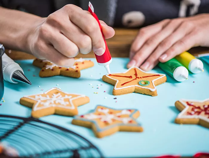 Woman decorating gingerbread Christmas cookies