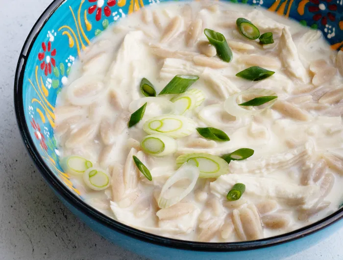 colorful blue painted bowl filled with a chicken orzo stew, garnished 