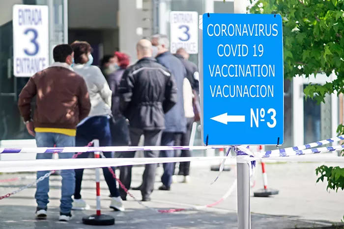 People waiting in line with a sign reading Coronavirus Covid 19 Vaccination