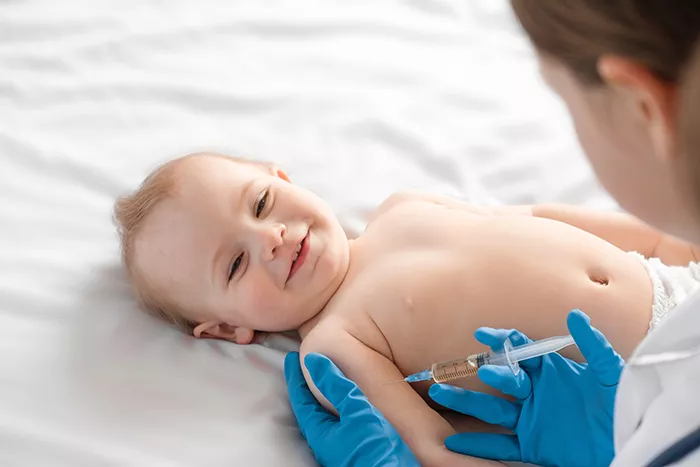 doctor giving a baby an injection while baby is laying on a white background
