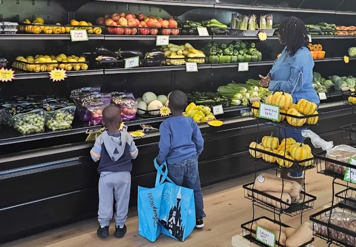 A mother and 2 young children shopping for fruits at the Fresh Start Market.