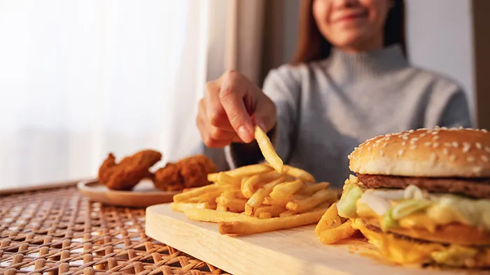 woman eating fries, wings and a burger