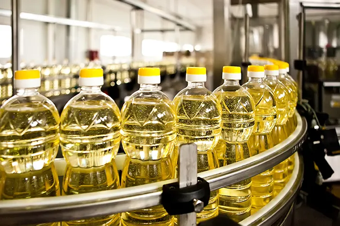 line of clear bottles of oil in a factory
