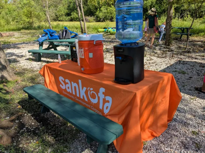 Water and supplies on a picnic table with a Sankofa tablecloth