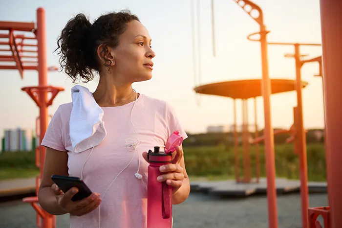 woman holding a water bottle and phone