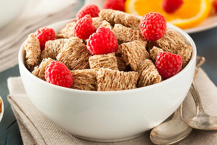 bowl full of shredded wheat and raspberries