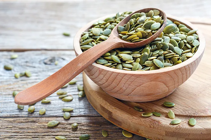 wooden bowl and spoon holing pumpkin seeds