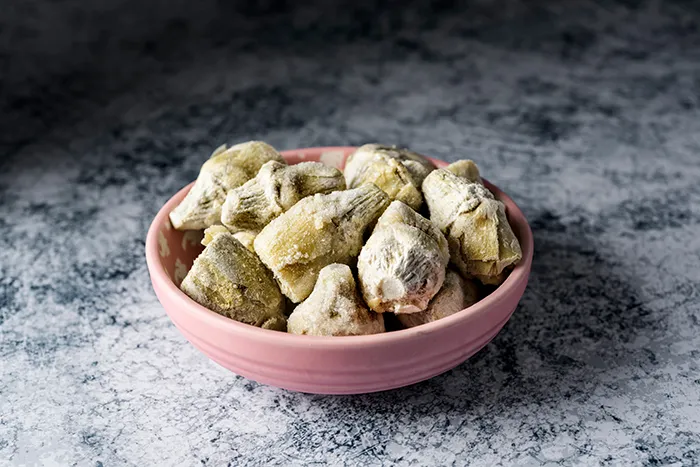 a pink bowl holding several frozen artichoke hearts