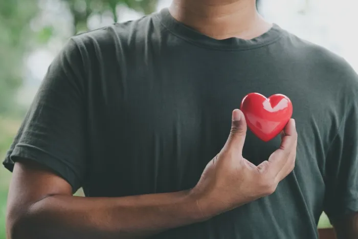 Man holds red heart to chest