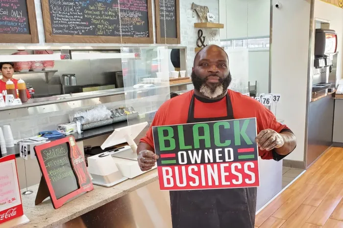 Big O Pork & Dreams; a man holds a sign reading "Black-owned business"