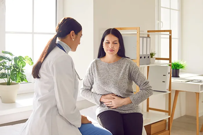 woman holding her stomach and talking to a doctor