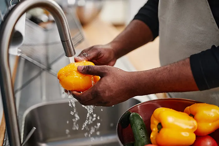 person washing pepper in a sink