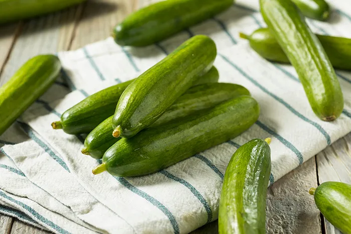 pile of Persian cucumbers on a striped tea towel
