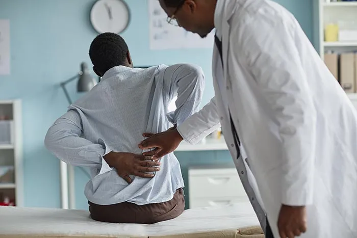 woman in doctors office showing doctor where the pain is in her lower back