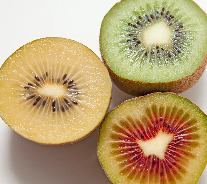 Clockwise from left: halved Gold kiwi, halved green kiwi, halved red kiwi.