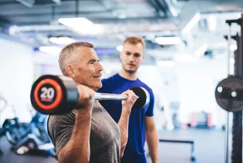 man holding barbell with personal trainer