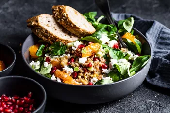 charcoal colored bowl filled with salad greens, fruit and bread