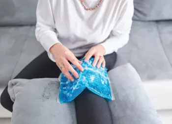 person icing and elevating their knee while sitting on a couch