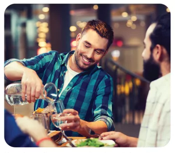 man filling a glass with water at restaurant