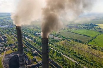 2 large smoke stacks with lots of green space in the background.